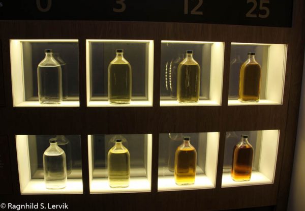 Bilde av åtte blenders sample flasker med whisky i forskjellige fargenyanser.